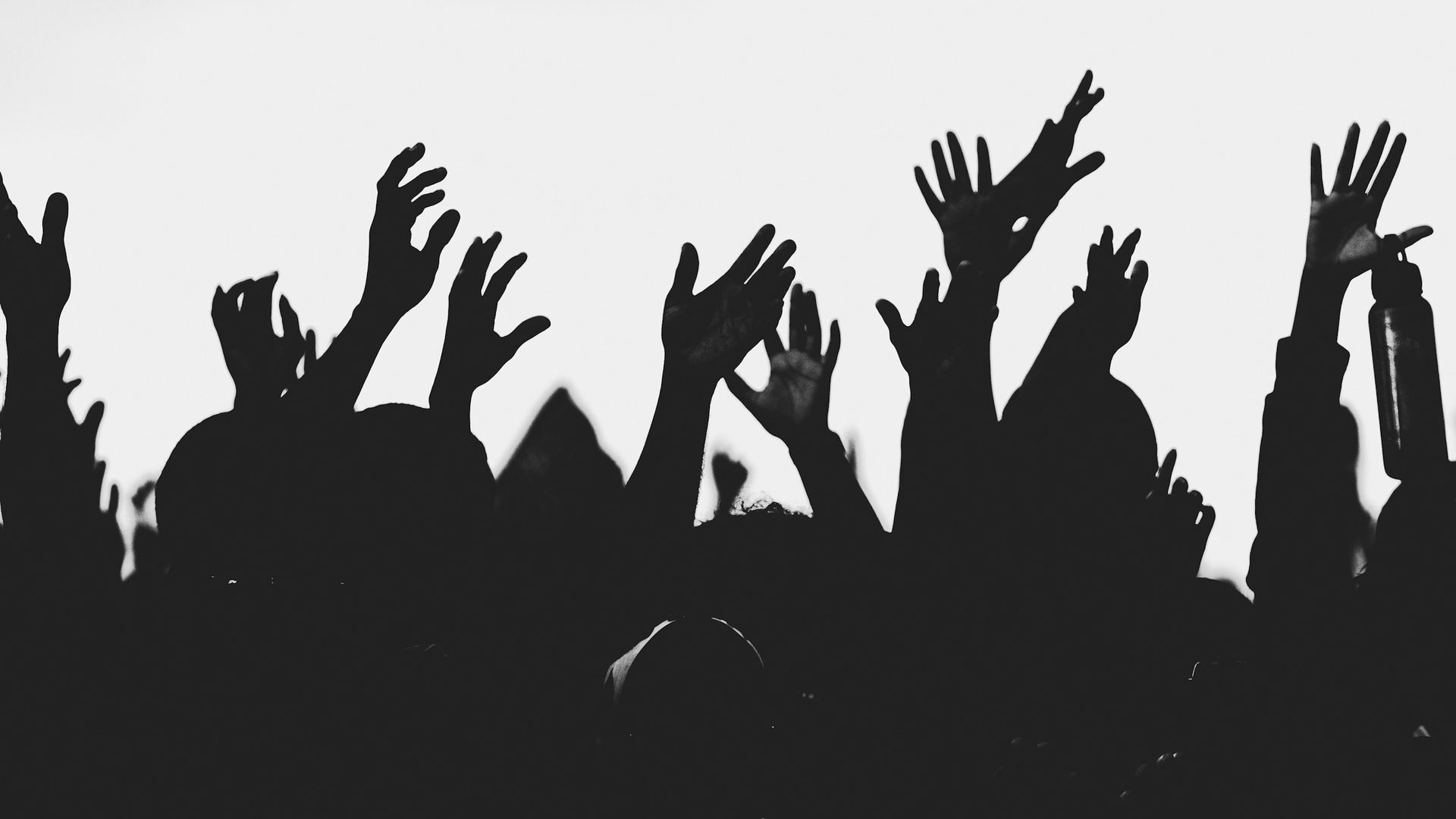 Silhouettes of young people with their hands raised