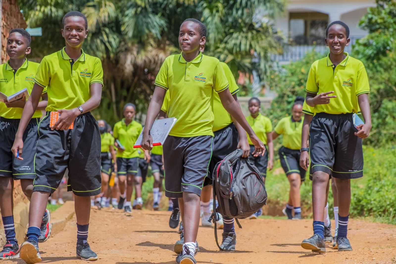 Ugandan secondary school students walking to class with books and backpacks